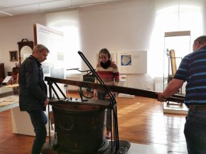 Die Handdruckspritze ist zurück im Museum. Restaurator Jens Zimmermann übergibt das Objekt an Museumsleiterin Antje Reichel und Detlef Preetz, Hausmeister im Museum.